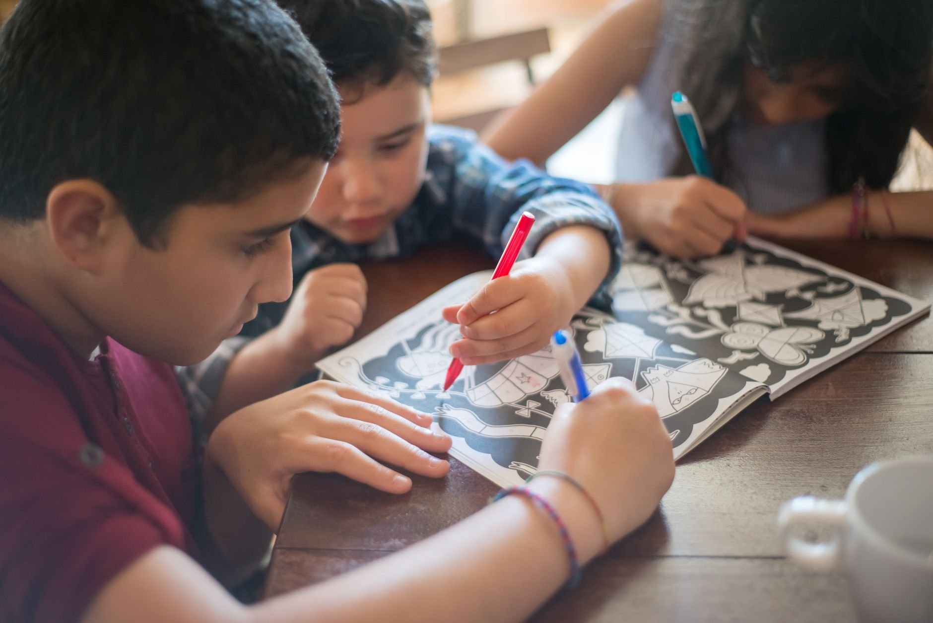 A group of children focused on coloring in an activity book together at a warm wooden table